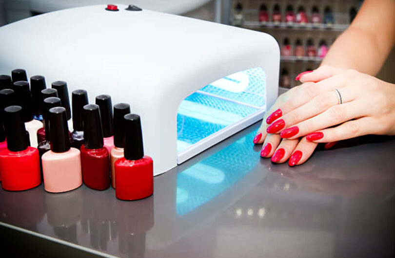 Manicure set in a beauty salon. Beautiful female hands. Machine for drying naroshchennyh nail UV lamp.
